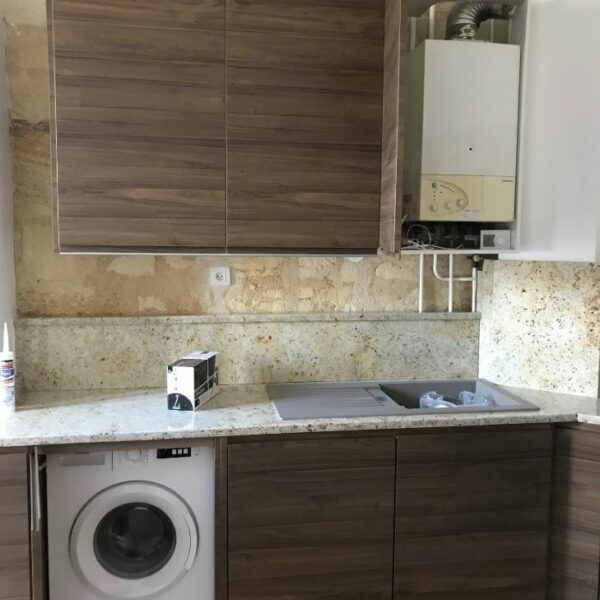 Cuisine moderne sur-mesure avec façades bois foncé et mur en pierre