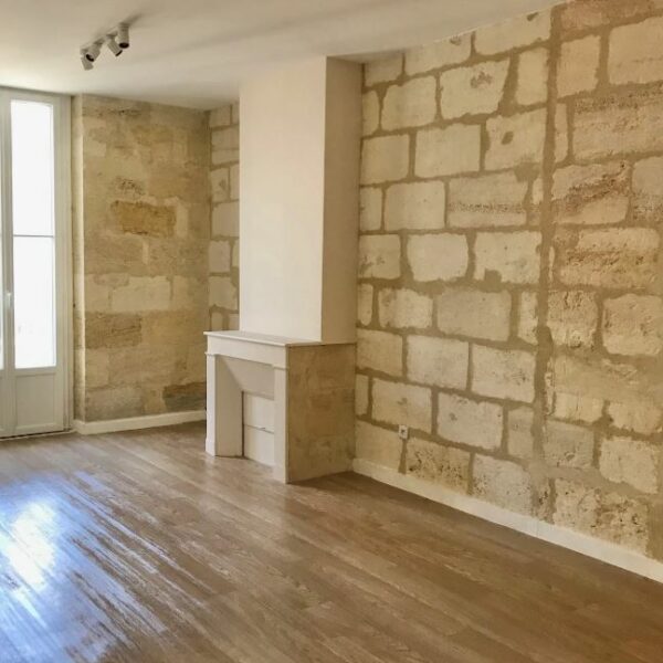 Salon rénové à Bordeaux avec mur en pierre apparente et parquet vitrifié