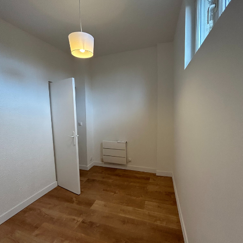 Chambre rénovée avec parquet bois clair et murs blancs